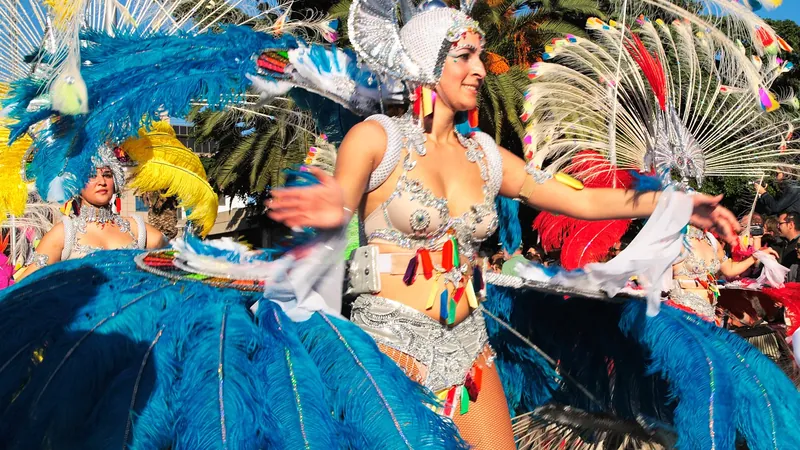 Bailarinas con trajes de plumas azules y blancas en un desfile de carnaval a pleno sol
