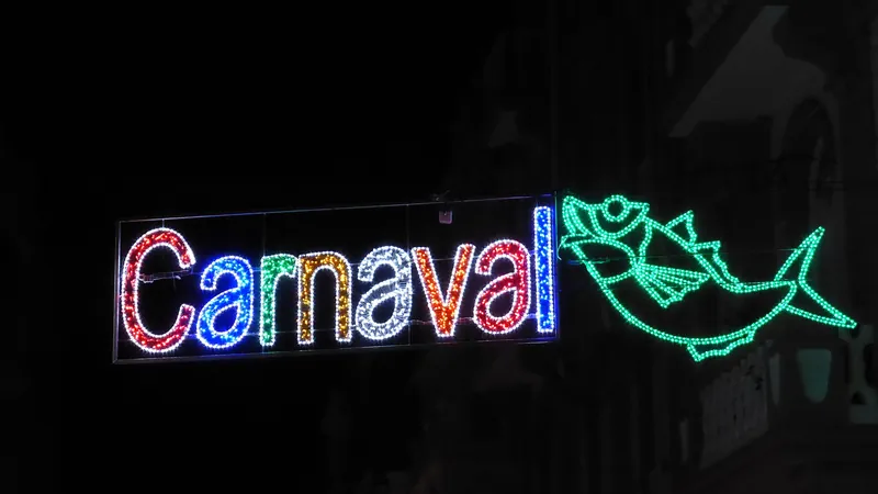 Letrero luminoso de «Carnaval» con una sardina de luces verdes sobre fondo negro