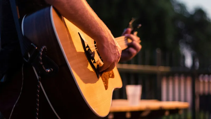 Primer plano de un músico tocando una guitarra acústica en un concierto íntimo