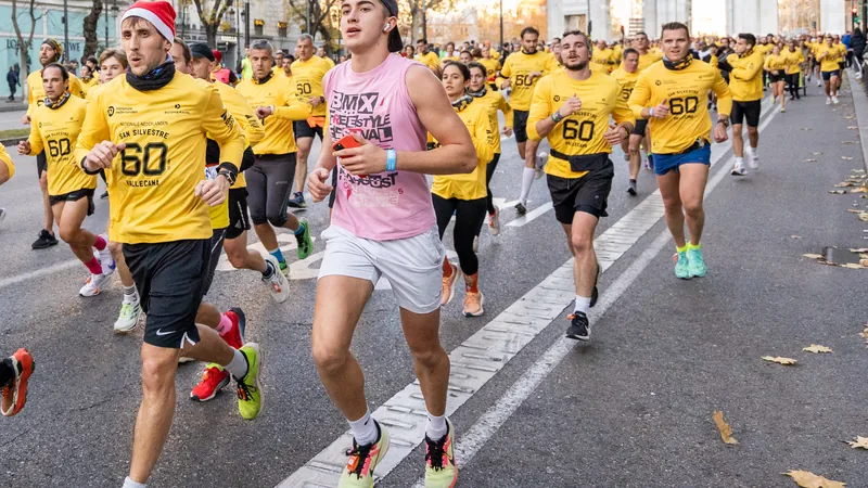 Miles de corredores con camiseta amarilla y gorros de Papá Noel en la San Silvestre Vallecana junto a la Puerta de Alcalá