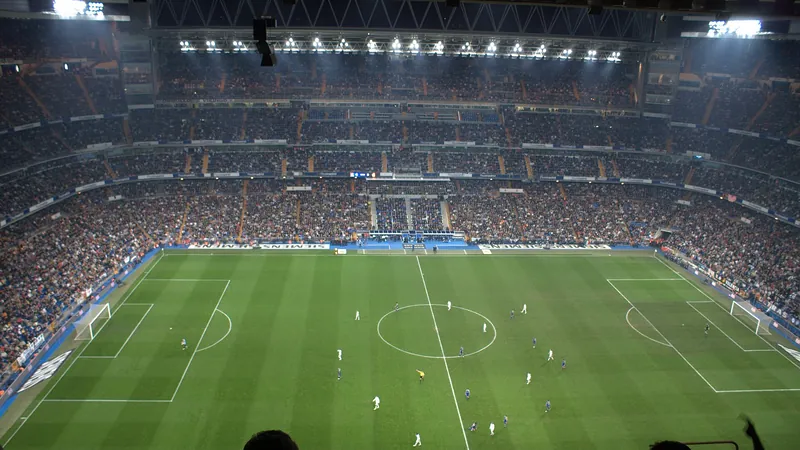 Estadio de fútbol lleno durante un partido nocturno, visto desde la grada alta