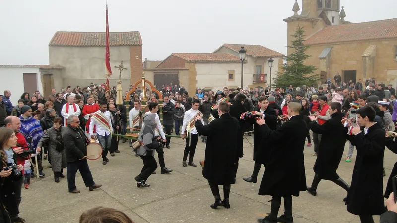 Vecinos bailando en corro en la plaza de un pueblo zamorano durante la fiesta del Zangarrón, con la iglesia al fondo