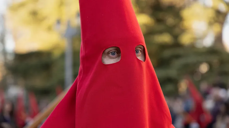 Nazareno con capirote rojo en primer plano durante una procesión de Semana Santa