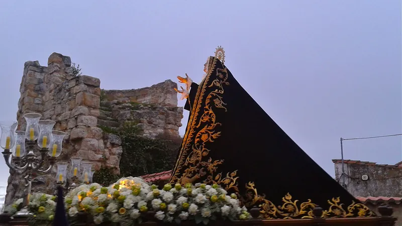 Paso de Semana Santa adornado con flores blancas y candelabros ante las murallas de Zamora al atardecer