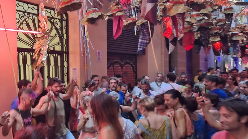 Gente bailando de noche en una calle engalanada durante la fiesta mayor de un barrio